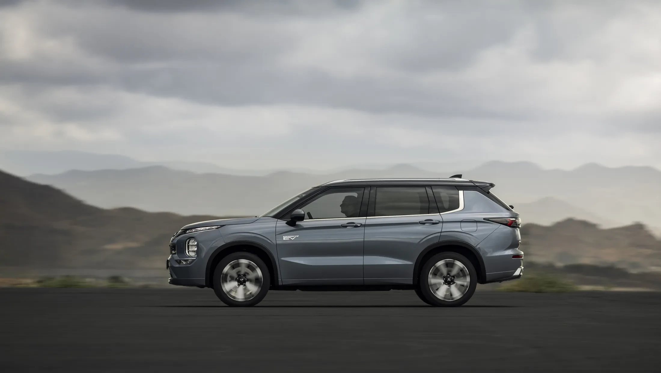 Mitsubishi Outlander PHEV MY2025 in woestijn met wolkenlucht