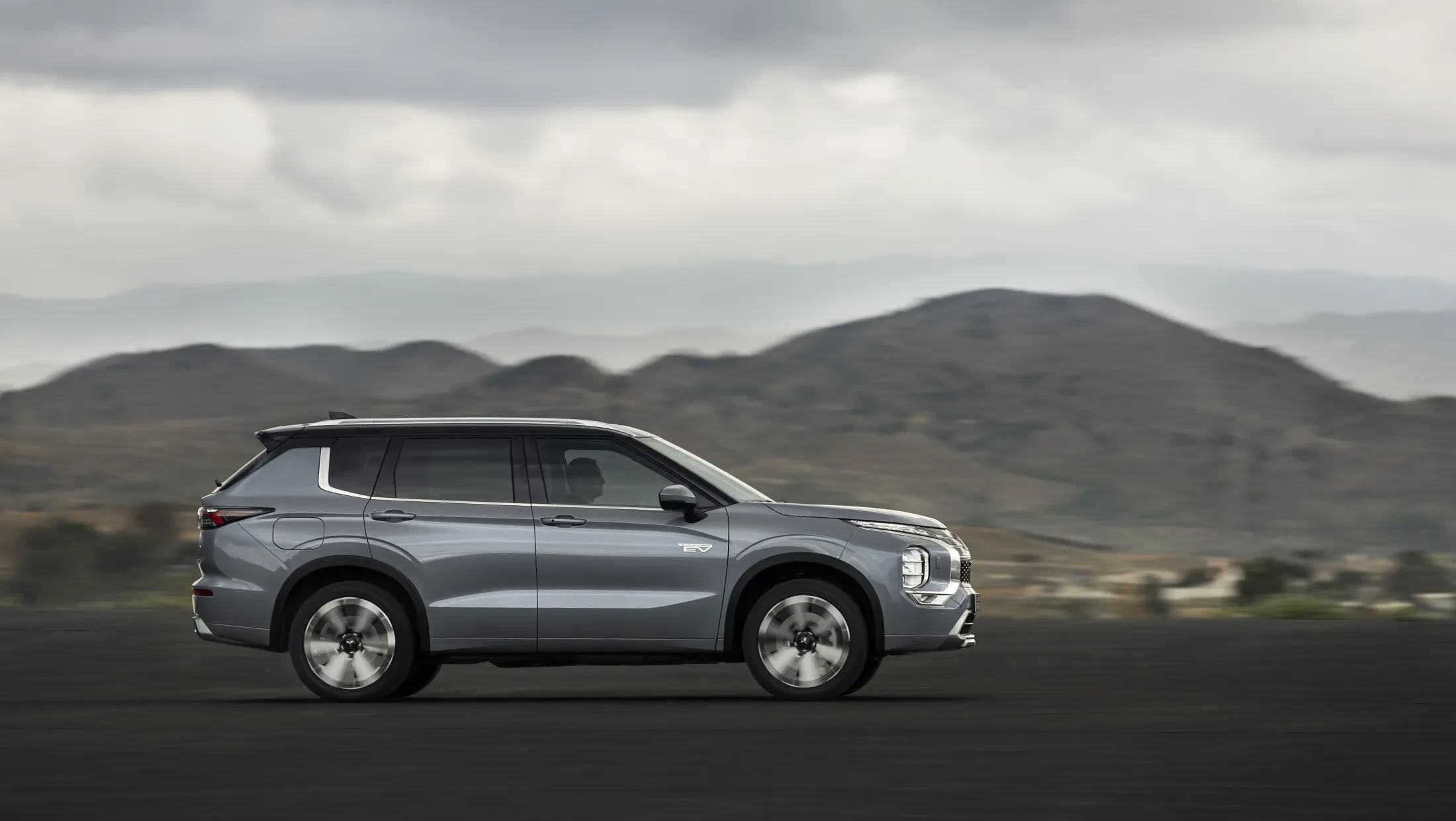 Mitsubishi Outlander PHEV MY2025 in woestijn met wolkenlucht