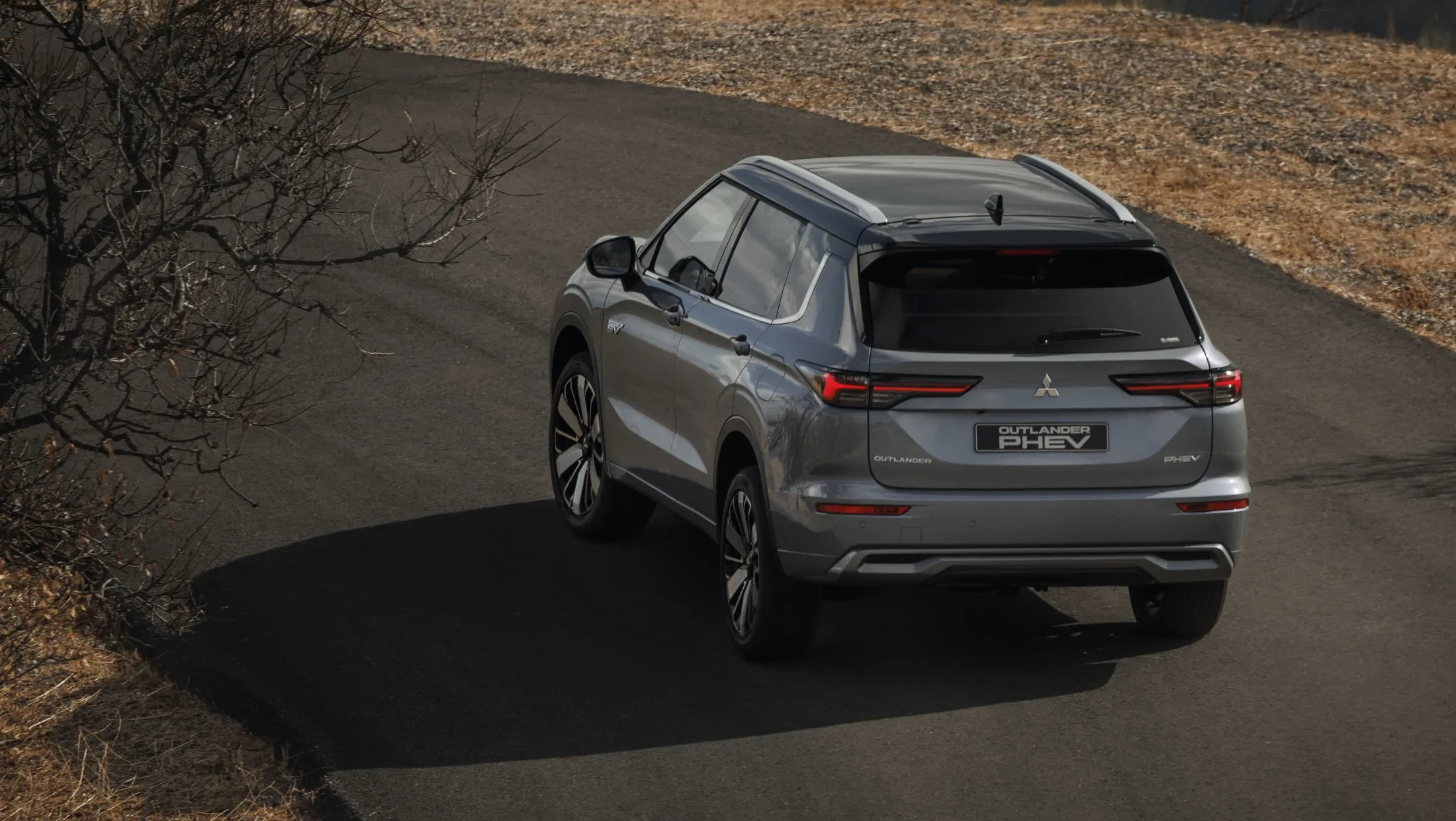 Mitsubishi Outlander PHEV MY2025 in woestijn met wolkenlucht